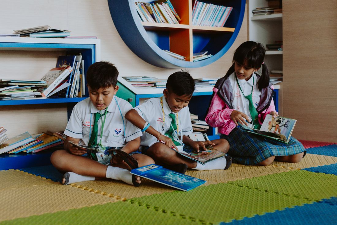Alunos lendo livros juntos na biblioteca